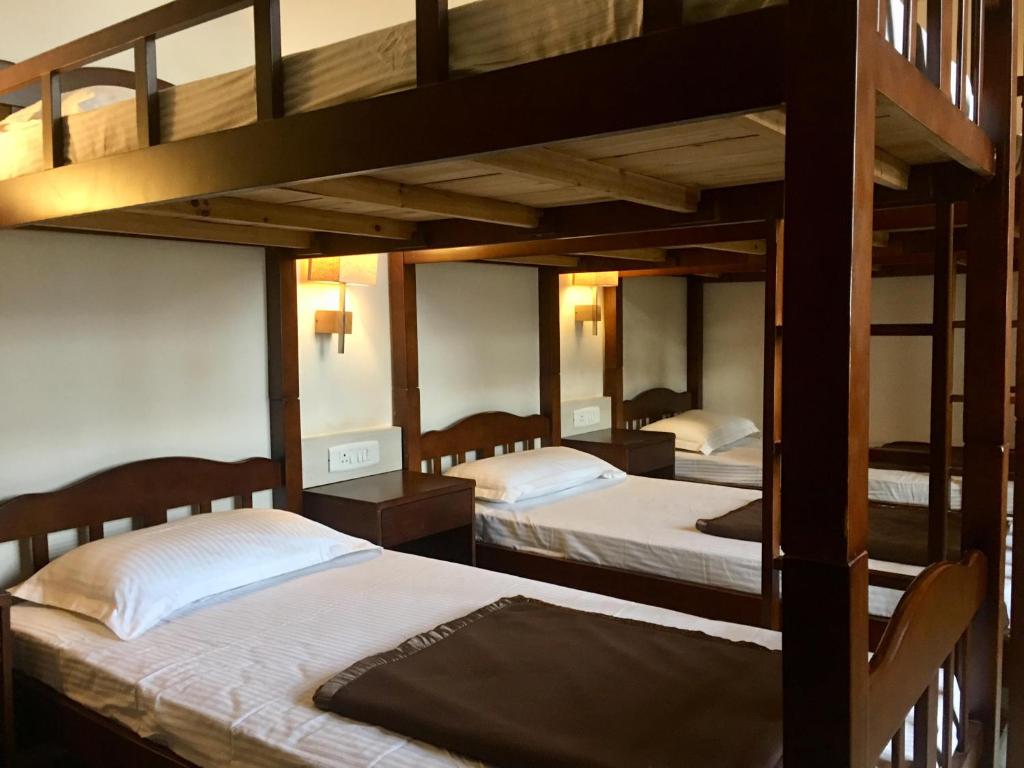 1 Schlafzimmer mit 3 Etagenbetten mit weißer Bettwäsche in der Unterkunft The KAHN Dormitory in Chikmagalur