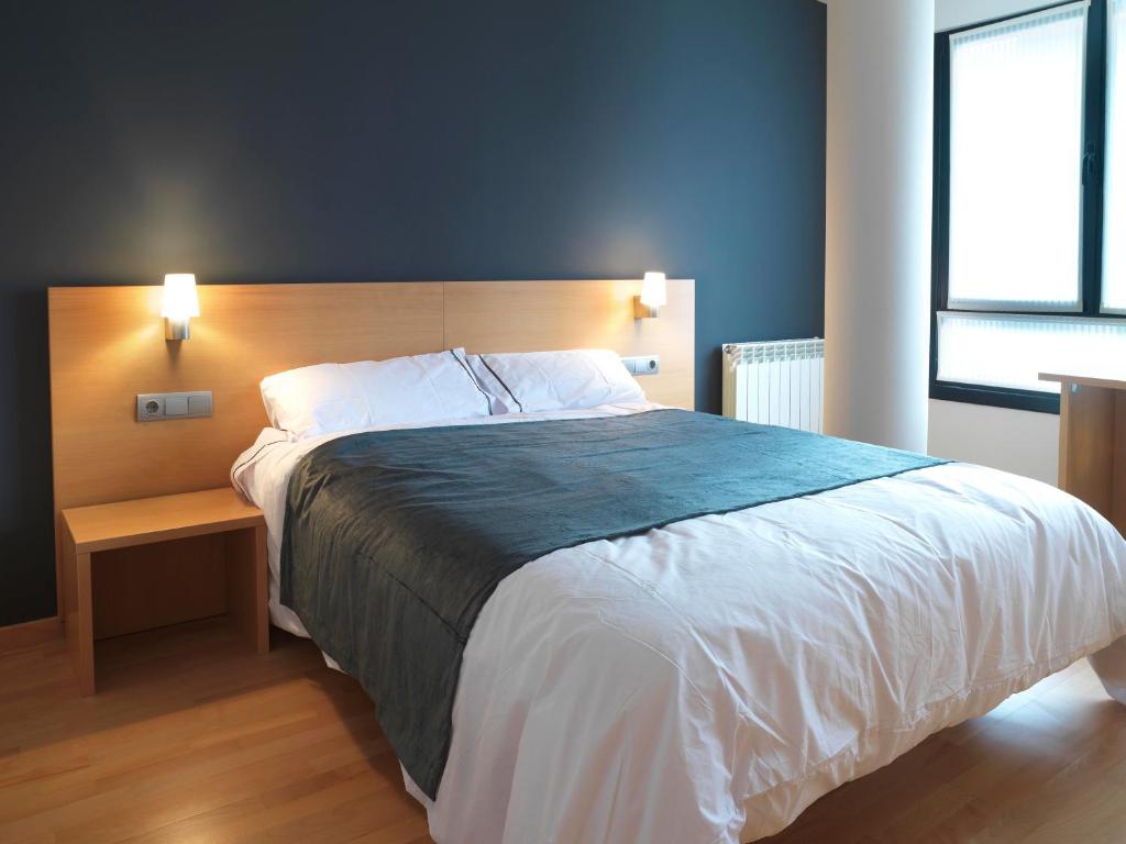 1 dormitorio con 1 cama grande y cabecero de madera en Hotel Txarriduna, en Elgóibar