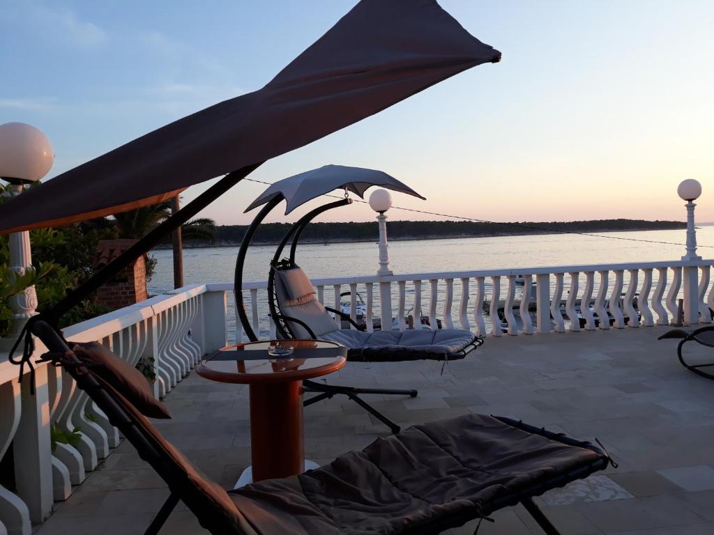 een patio met een tafel, een stoel en een parasol bij Apartments and Rooms Vinko in Barbat na Rabu