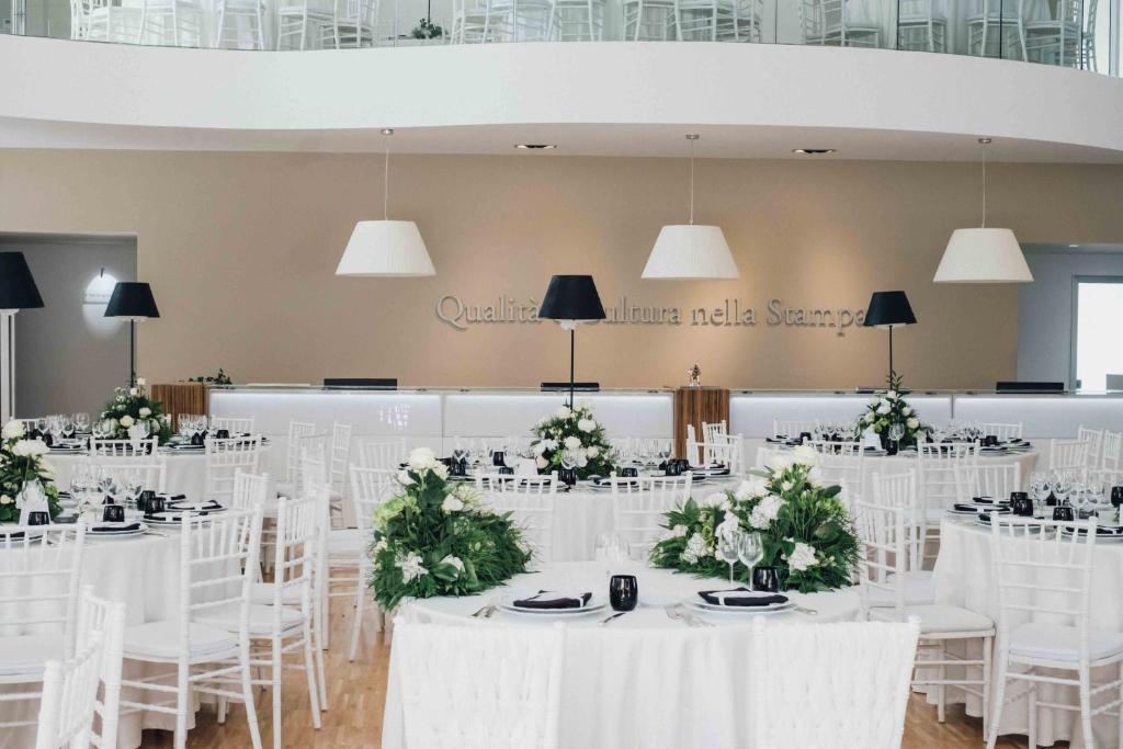 a banquet hall with white tables and chairs with flowers at Il Borghetto Resort & Spa in Tropea