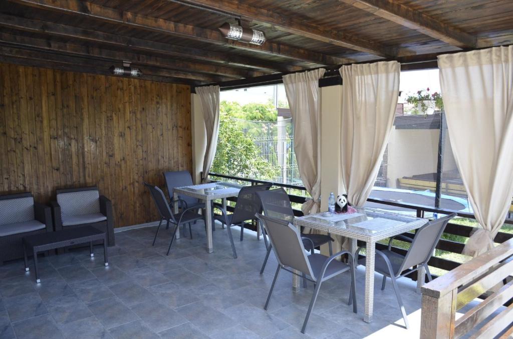 uma sala de jantar com mesas, cadeiras e janelas em Vila Danly em Costinesti