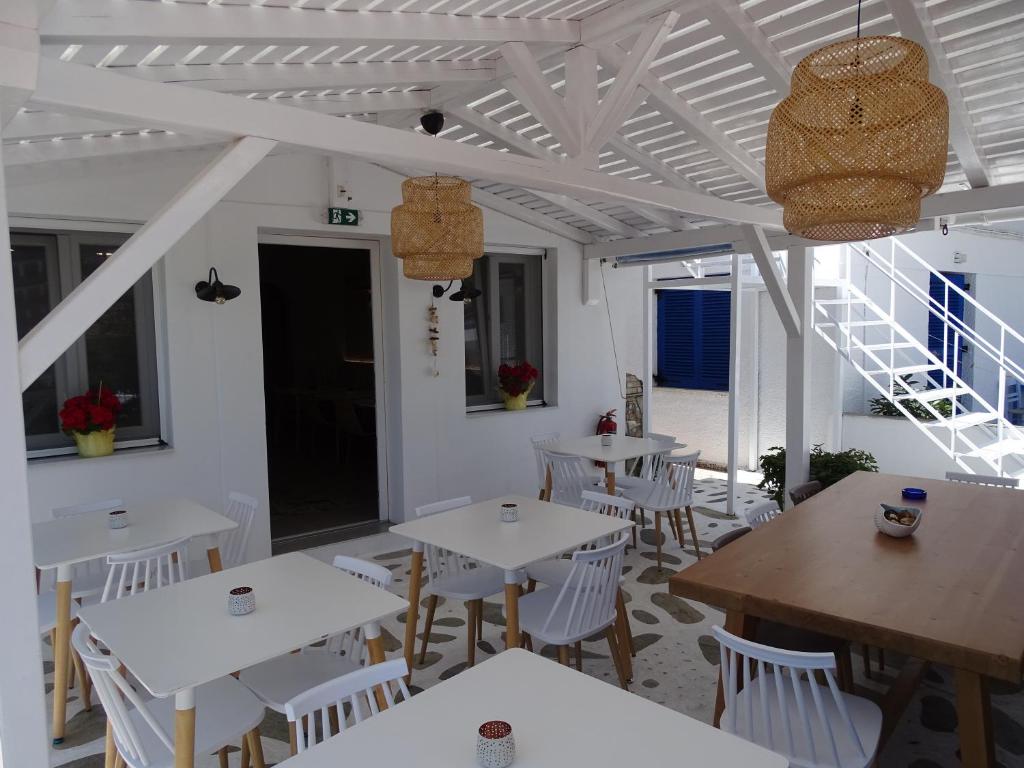 ein Restaurant mit weißen Tischen und weißen Stühlen in der Unterkunft Galini Hellenic Hospitality in Patitiri