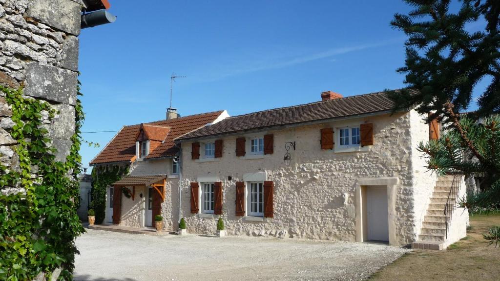 een groot wit stenen huis met bruine daken bij La Chaumerie in Chenevelles