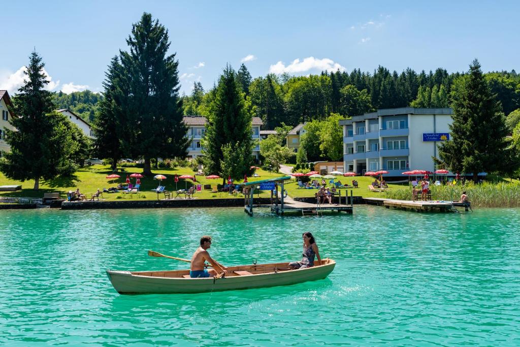 2 personnes dans un bateau sur un lac dans l'établissement Strandhotel Schabus, à Velden am Wörther See