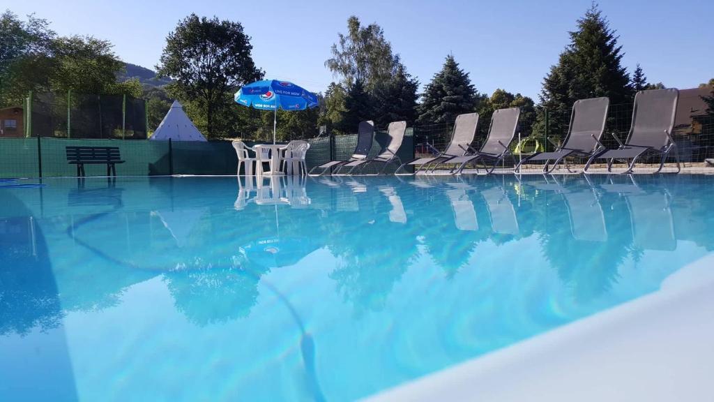 eine Gruppe von Stühlen und einem Sonnenschirm in einem Pool in der Unterkunft Hotel Formule in Děčín