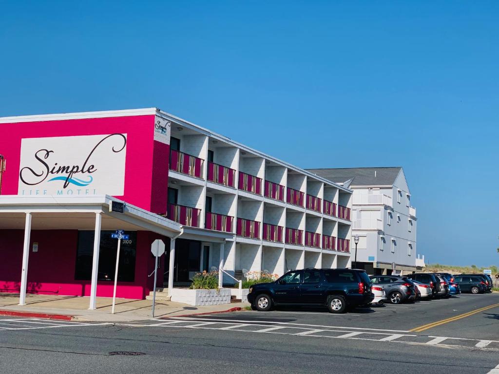 un grand bâtiment avec des voitures garées dans un parking dans l'établissement Simple Life Motel, à Ocean City