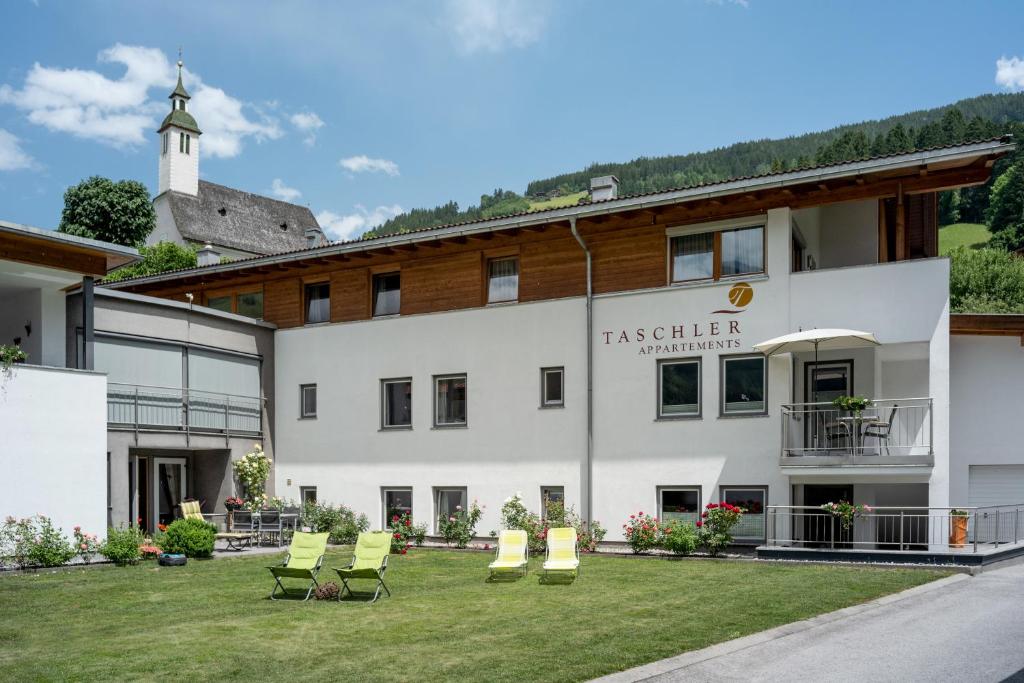 um grande edifício branco com cadeiras no quintal em Ferienwohnung Taschler em Ramsau im Zillertal