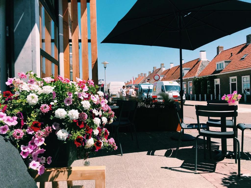 een tafel en stoelen met bloemen en een parasol bij Boutique Hotel Charley's in Westkapelle