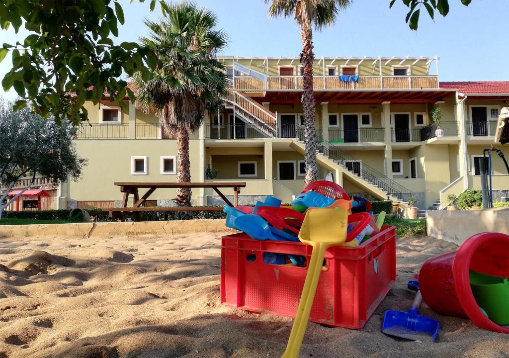 um parque infantil na areia em frente a um hotel em Honigtal Farmland em Agios Georgios Pagon