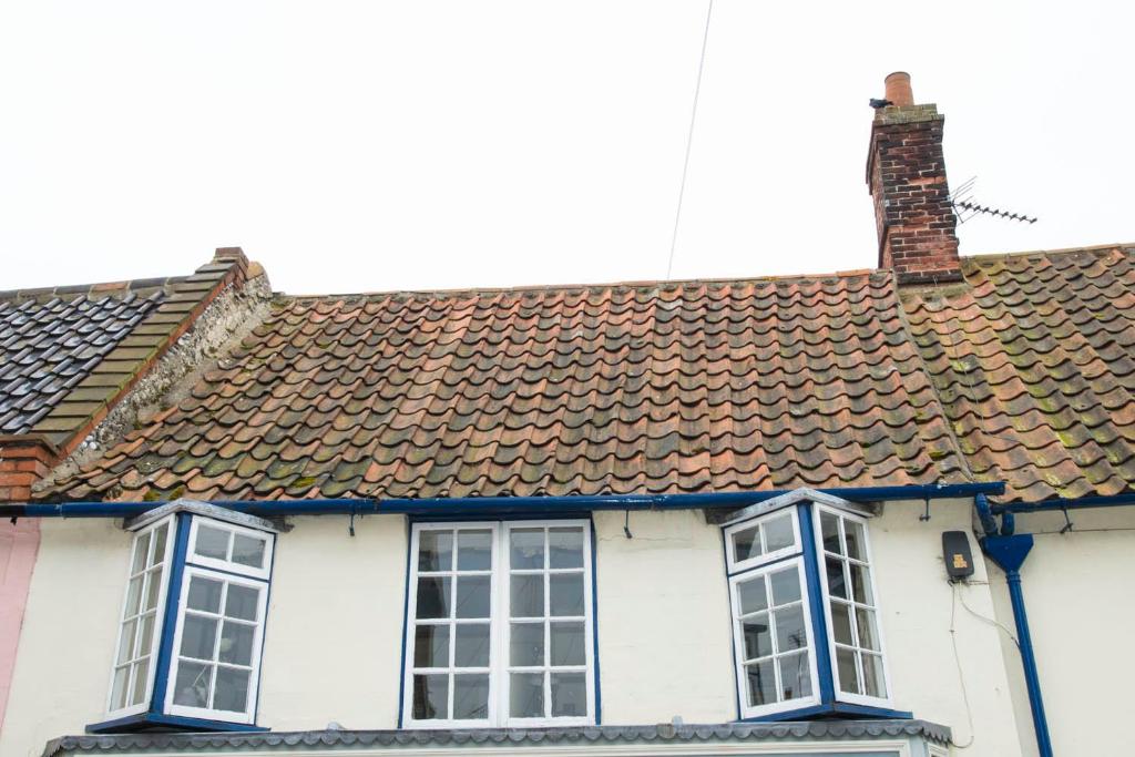 a white house with two windows and a roof at The Plover in Blakeney