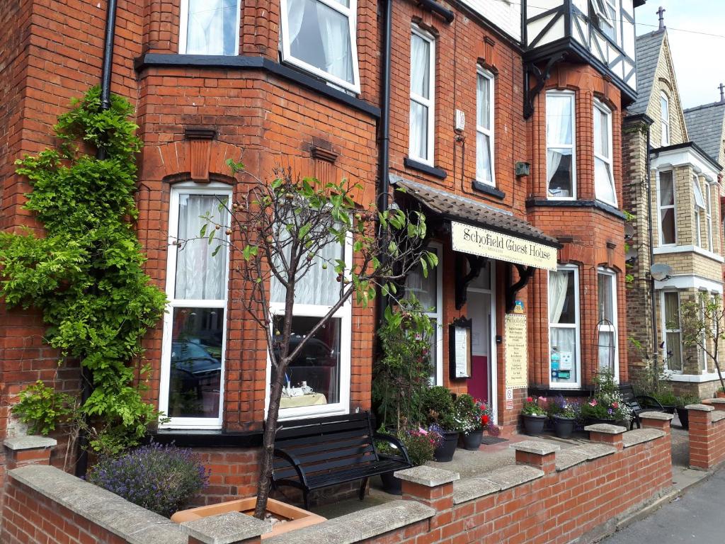 a brick building with a bench in front of it at Schofield Guest House in Bridlington