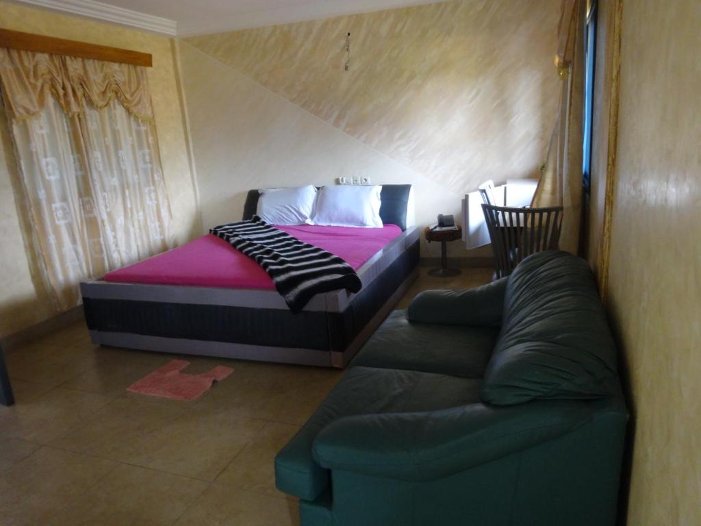 Meka Hotel في كارا: غرفة نوم بسرير واريكة