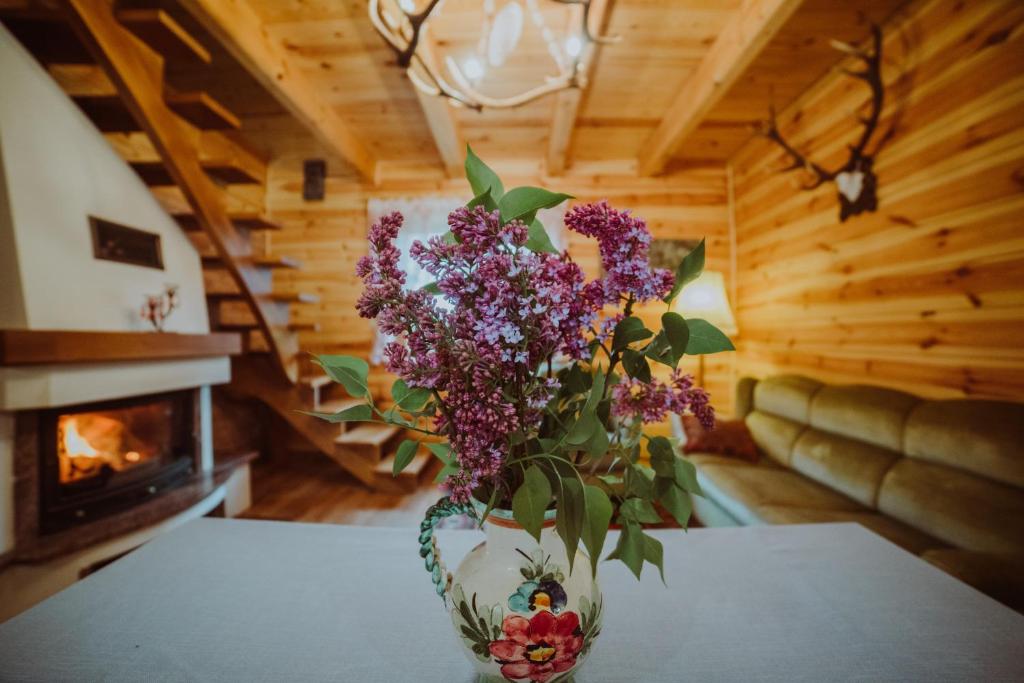 a vase of purple flowers on a table with a fireplace at Trzy Stawy in Pysznica