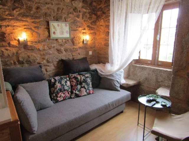 uma sala de estar com um sofá e uma parede de pedra em Casa do Forno em Almeida