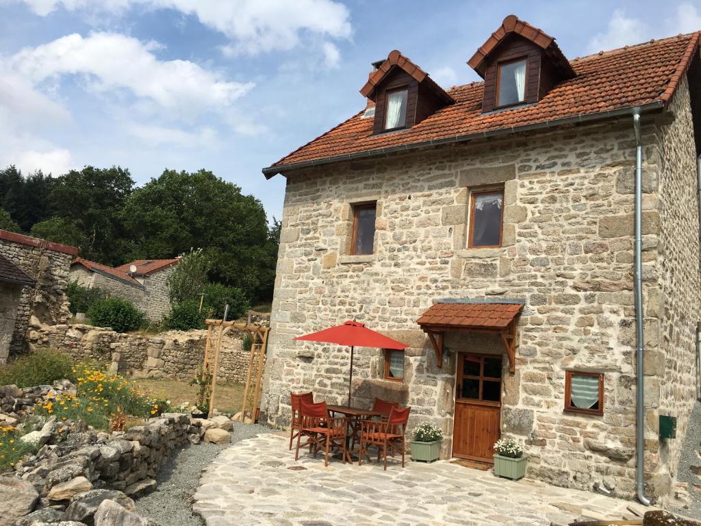 une maison en pierre avec une table et des chaises dans l'établissement Maison de Bois Royale, à Royère-de-Vassivière