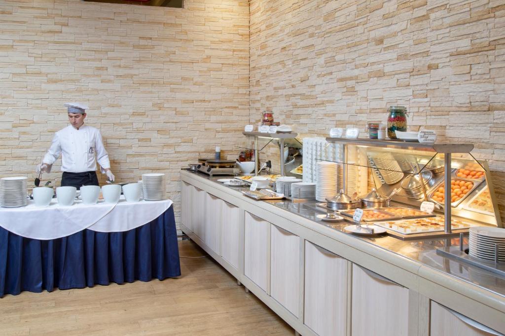 a chef is standing in a kitchen with a buffet at New Peterhof Hotel in Petergof