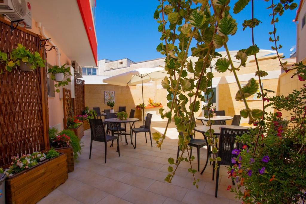 un patio esterno con tavoli, sedie e fiori di b&b Rita, nel cuore del Salento a Cavallino di Lecce