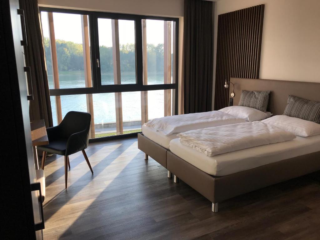 1 dormitorio con 2 camas, silla y ventanas en Hotel Donauhof Mauthausen, en Mauthausen