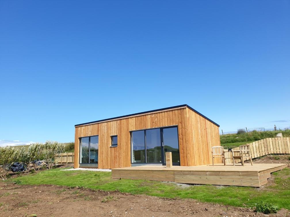 ein Holzhaus mit einer Terrasse und Fenstern in der Unterkunft Flora's Cliff View in Kilmuir