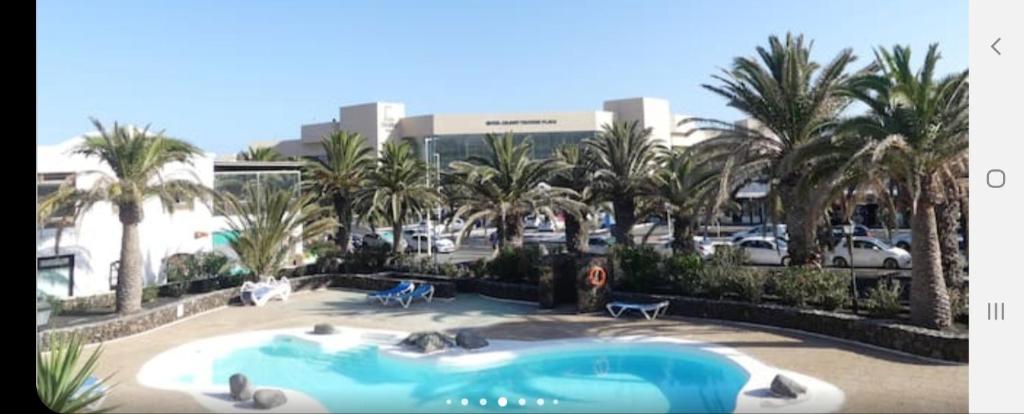 a swimming pool with palm trees and a parking lot at CASA JABLILLO in Costa Teguise