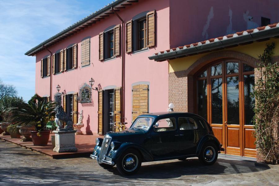 a black car parked in front of a pink building at Rustico la Pioppeta in Cascina