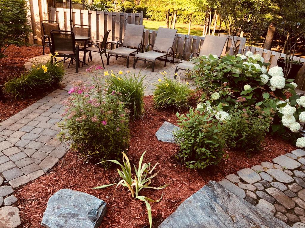 a patio with chairs and flowers in a yard at Relais St-Denis in Saint-Sauveur-des-Monts