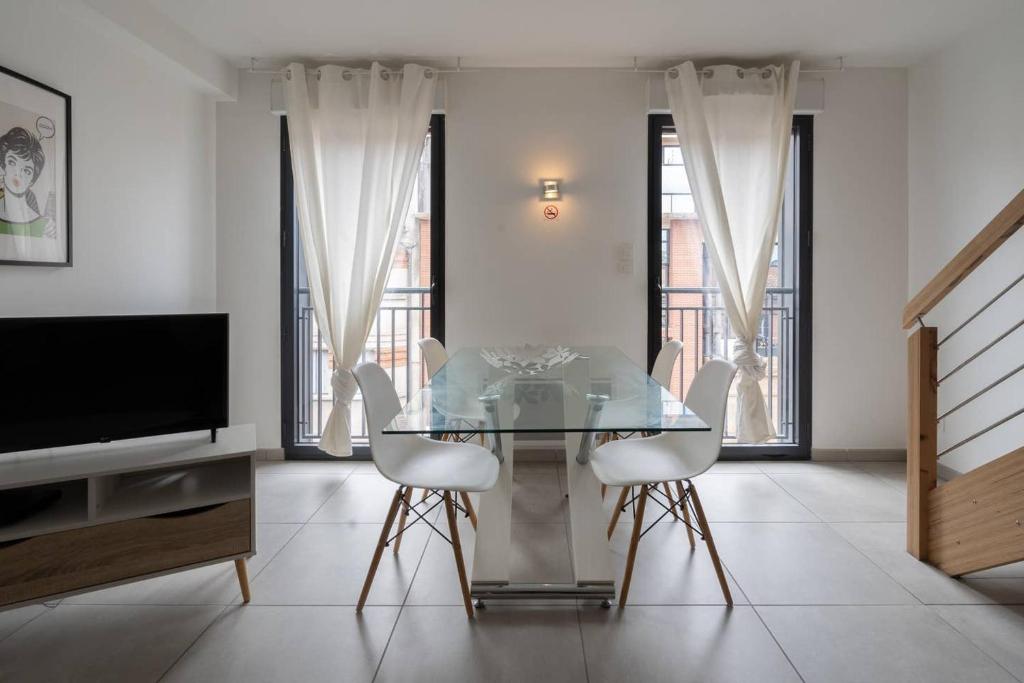 een eetkamer met een glazen tafel en 2 witte stoelen bij 303 - Appartement Duplex Moderne - Jeanne d'Arc, Toulouse in Toulouse