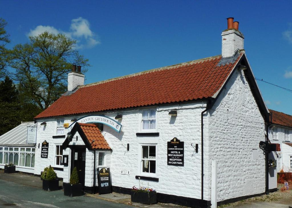 un bâtiment blanc avec un toit rouge dans l'établissement Ganton Greyhound Inn, à Ganton