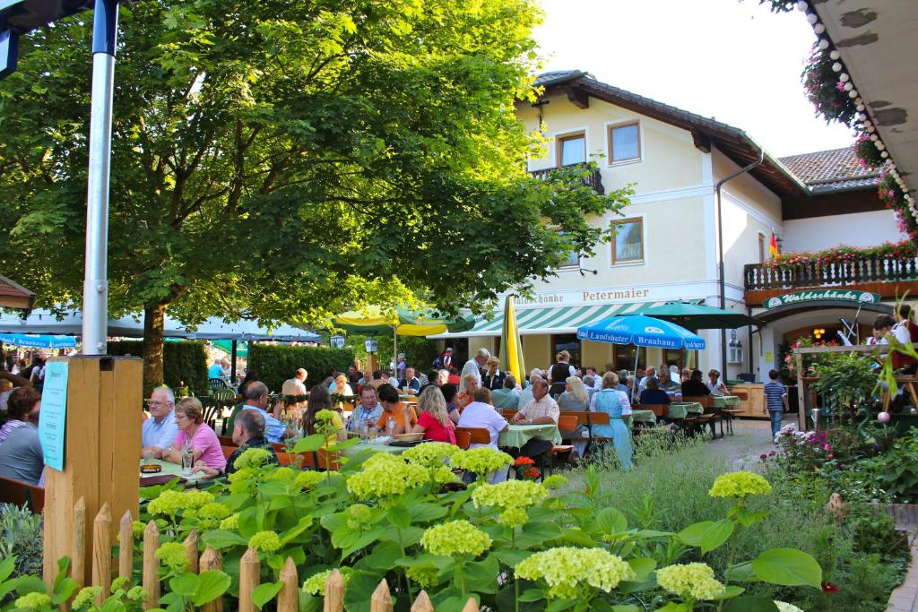 un grupo de personas sentadas en mesas en un jardín en Land-gut-Hotel Gasthof Waldschänke, en Altfraunhofen