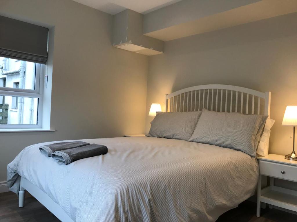 una camera da letto con un grande letto bianco con due lampade di Bush House Accommodation - The Courthouse Apartment a Bushmills