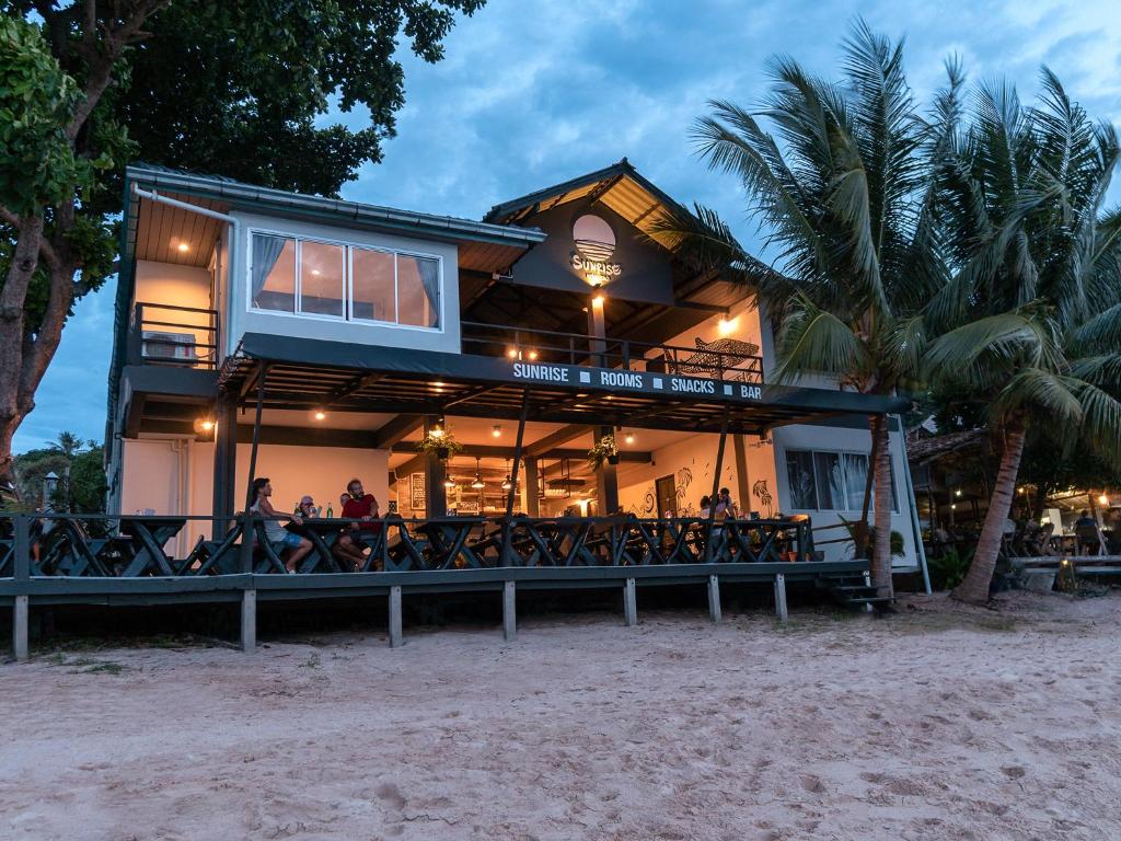 ein Haus am Strand mit Leuten auf dem Deck in der Unterkunft Sunrise Koh Tao in Ko Tao