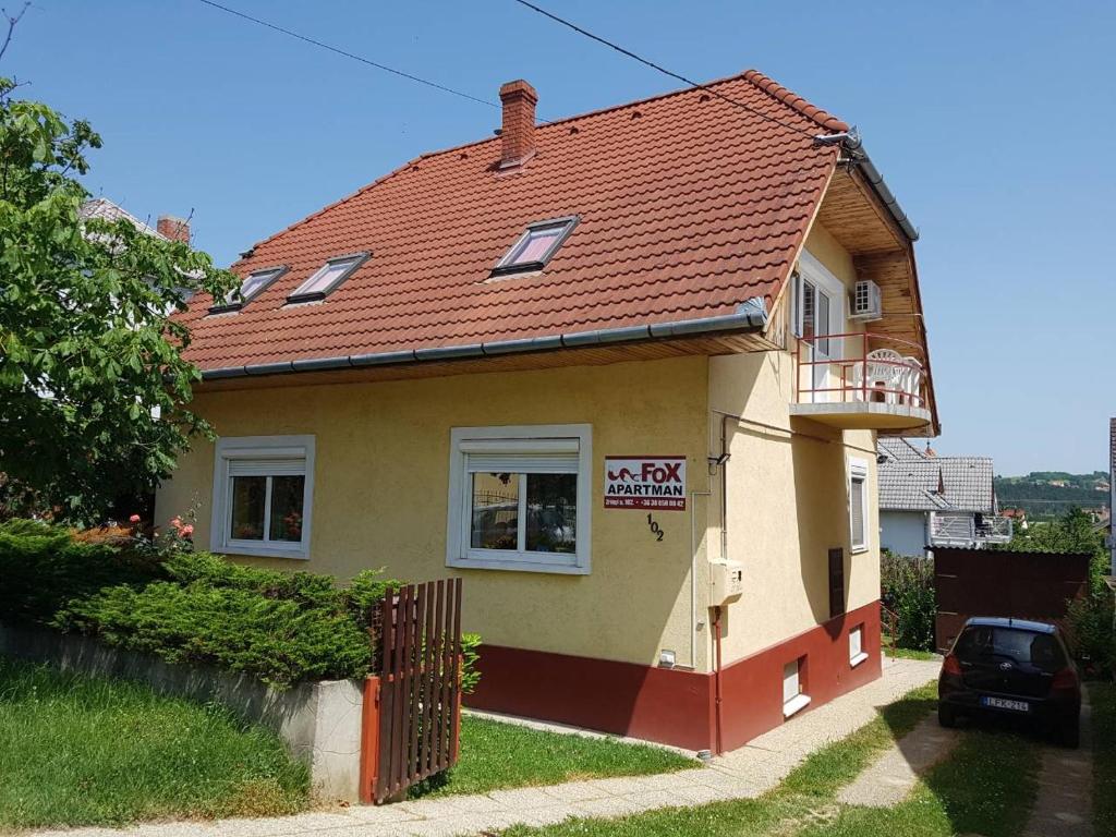 a small yellow house with a red roof at Fox Apartmanok in Hévíz