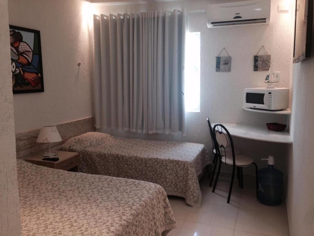 Cette chambre comprend deux lits et un bureau avec un four micro-ondes. dans l'établissement Apartamentos Hotel Marinas, à Tamandaré