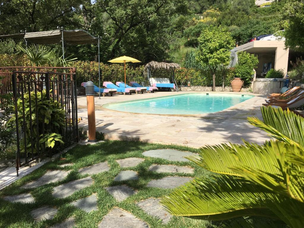 einen Pool in einem Garten mit Stühlen und einem Sonnenschirm in der Unterkunft La Romarine in Falicon