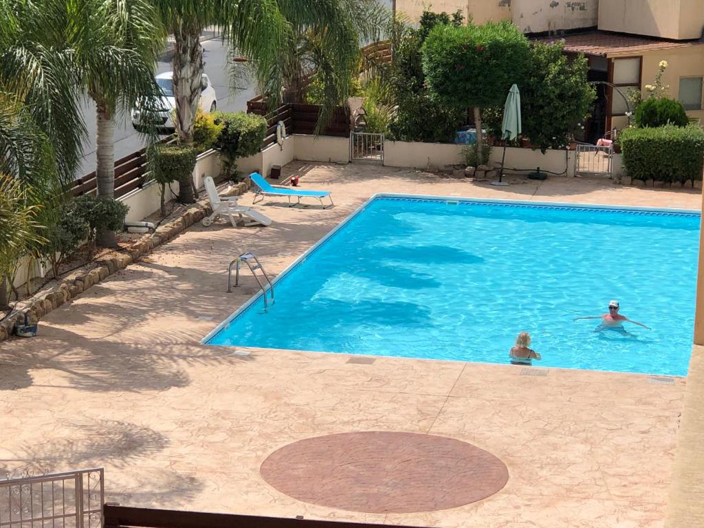 een zwembad met twee personen in het water bij Private apartment at Aristo Universe III with pool in Paphos City