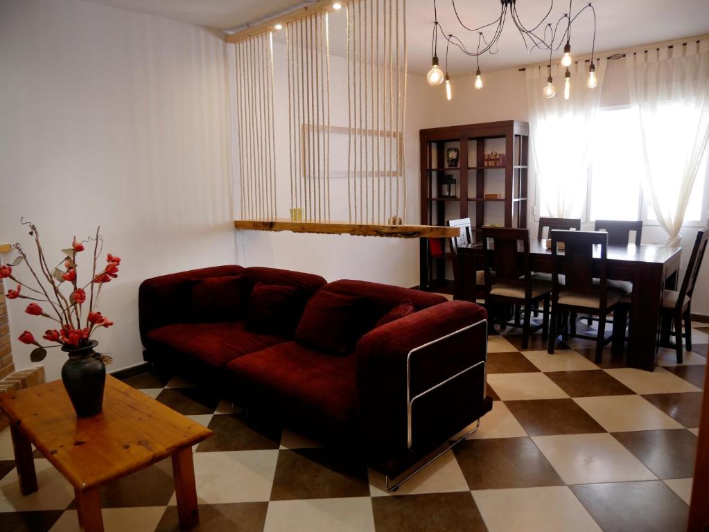 a living room with a red couch and a table at Casa Rural el Reencuentro "Grupo Mirando a Gredos" in Cadalso de los Vidrios