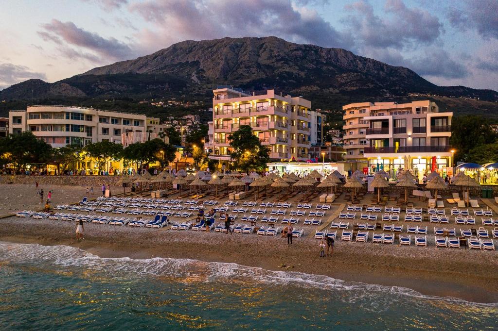una spiaggia con un gruppo di sedie e edifici di Sunset Hotel a Dobra Voda