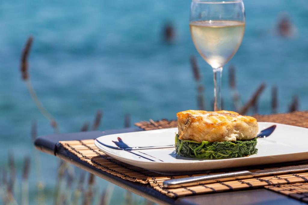 a plate of food and a glass of wine on a table at Spetses Hotel in Spetses