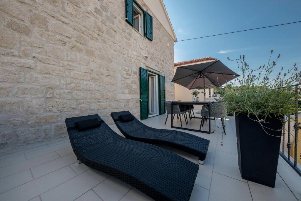 eine Terrasse mit einem Tisch, Stühlen und einem Sonnenschirm in der Unterkunft Villa Santino in Rab