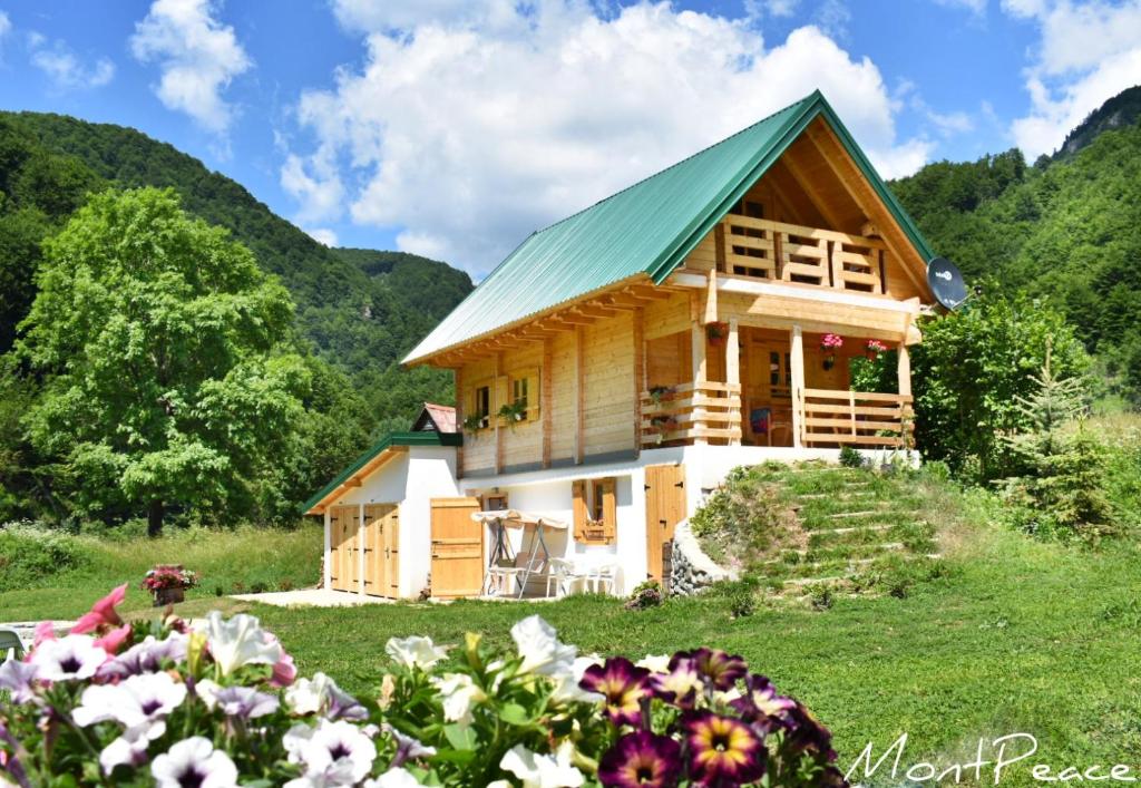 a wooden house with a green roof in a field of flowers at Mountain Lodge Mont Peace in Kolašin