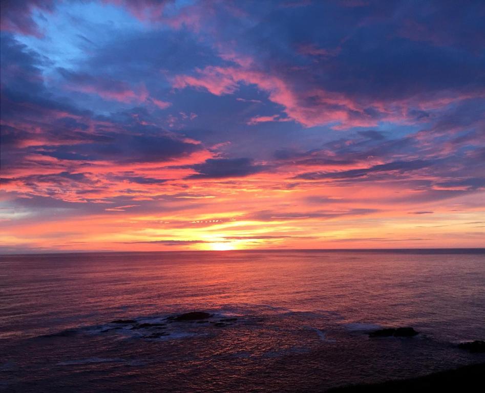 una puesta de sol sobre el océano con un cielo nublado en Nyksund Apartments Marihaugen, en Nyksund