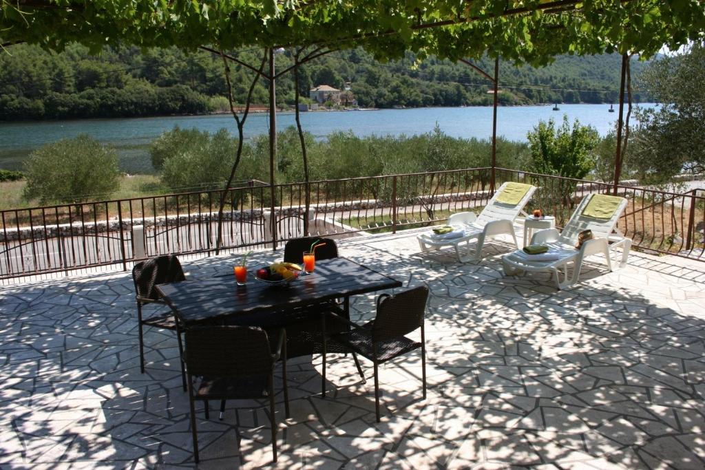 a table and chairs on a patio with a view of a lake at Apartment Marin - 40m from sea in Ston