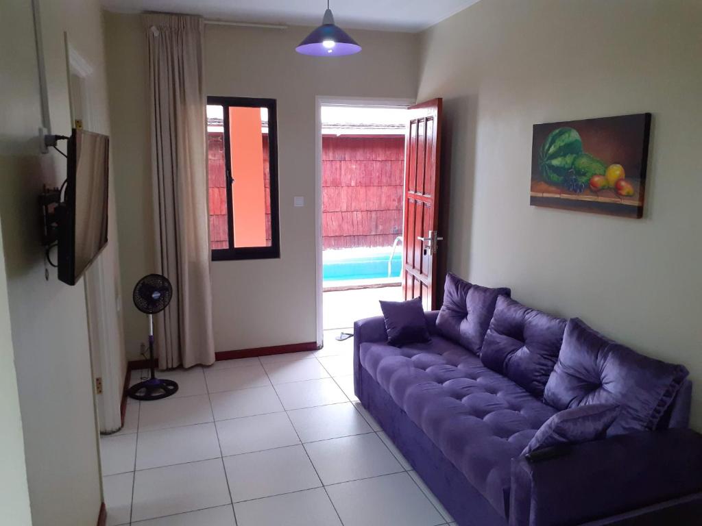 een woonkamer met een paarse bank en een raam bij Max Garden and Pool in Paramaribo