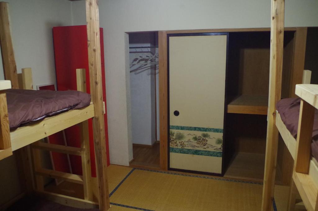 a room with two bunk beds and a door at Kusatsu Onsen Guesthouse Gyoten in Kusatsu