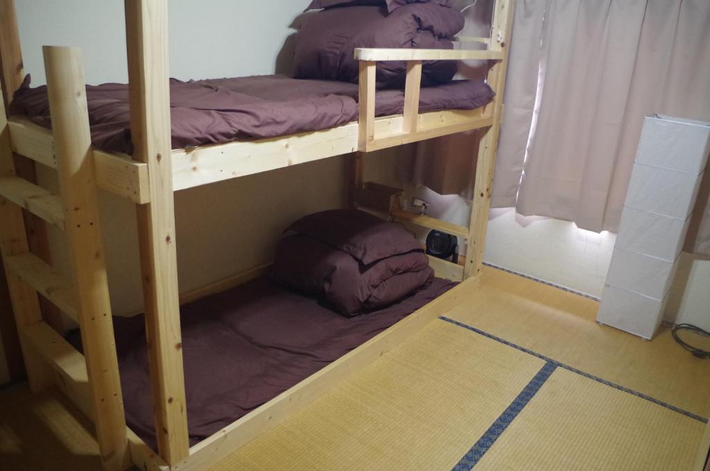 two bunk beds in a room with a floor at Kusatsu Onsen Guesthouse Gyoten in Kusatsu