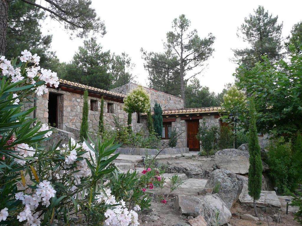 una casa de piedra en medio de un jardín en La Quinta de los Enebrales, en El Hoyo de Pinares