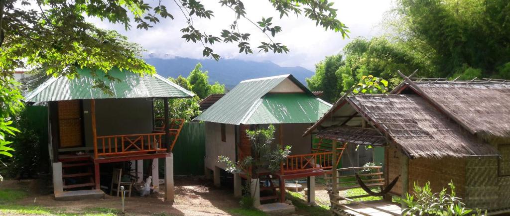 un groupe de petites maisons avec des montagnes en arrière-plan dans l'établissement KK Hut, à Pai
