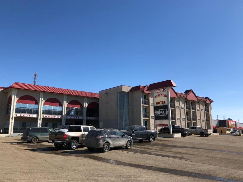 a parking lot with cars parked in front of a building at Westwind Motor Inn Hotel in Drayton Valley