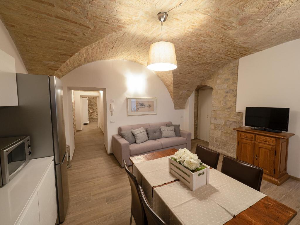 salon z kanapą i stołem w pokoju w obiekcie Residenza Porta Perlici Assisi Apartment w Asyżu