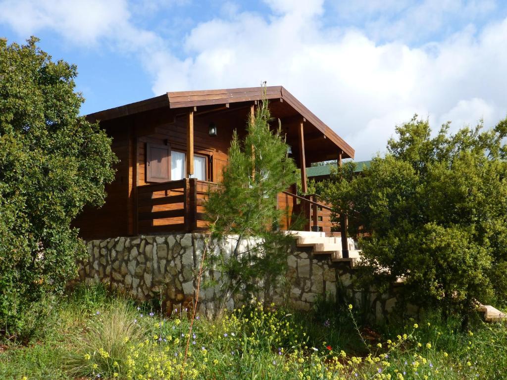 a wooden house with a stone wall at Mountain Breeze Lodge & Resort in Al Salt